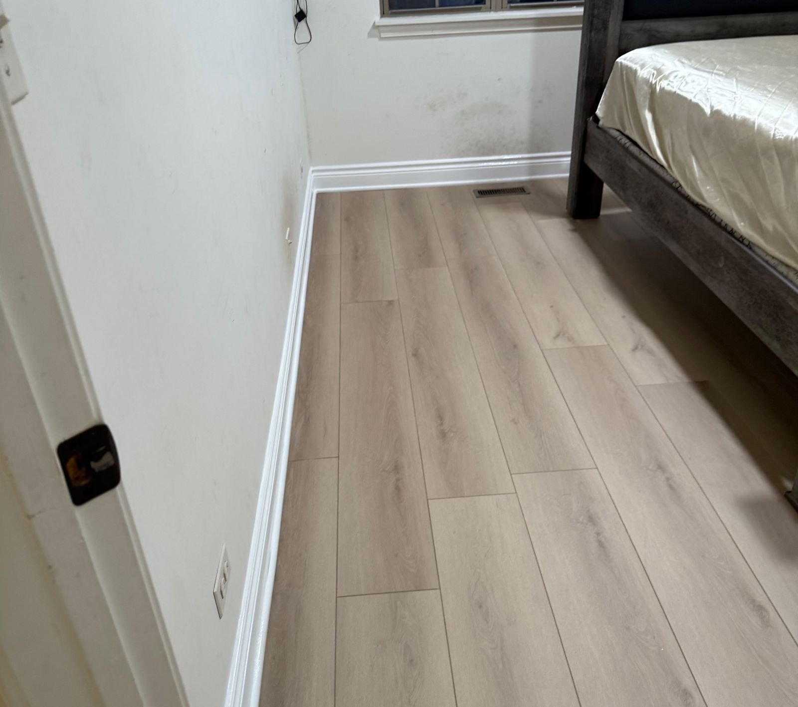 After: the same bedroom with a new light vinyl plank floor