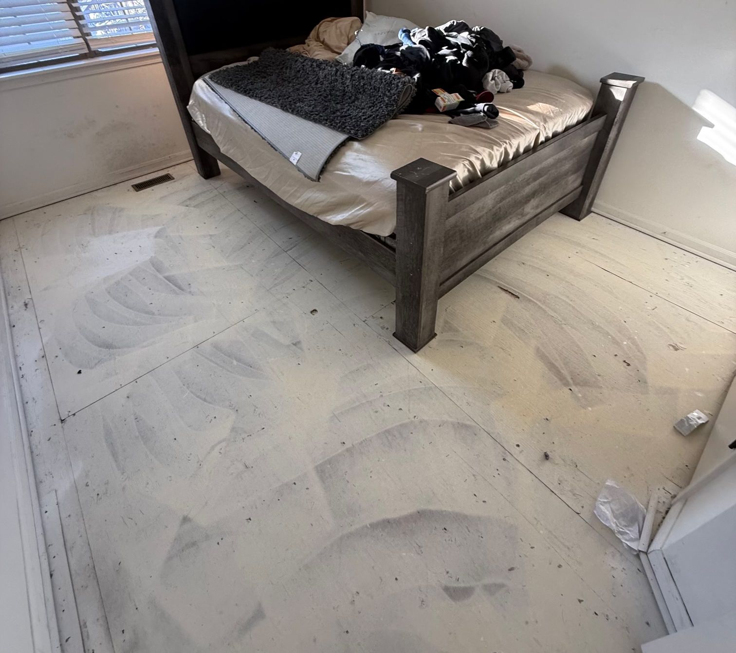 Before: bedroom with carpet pulled up and bare subfloor