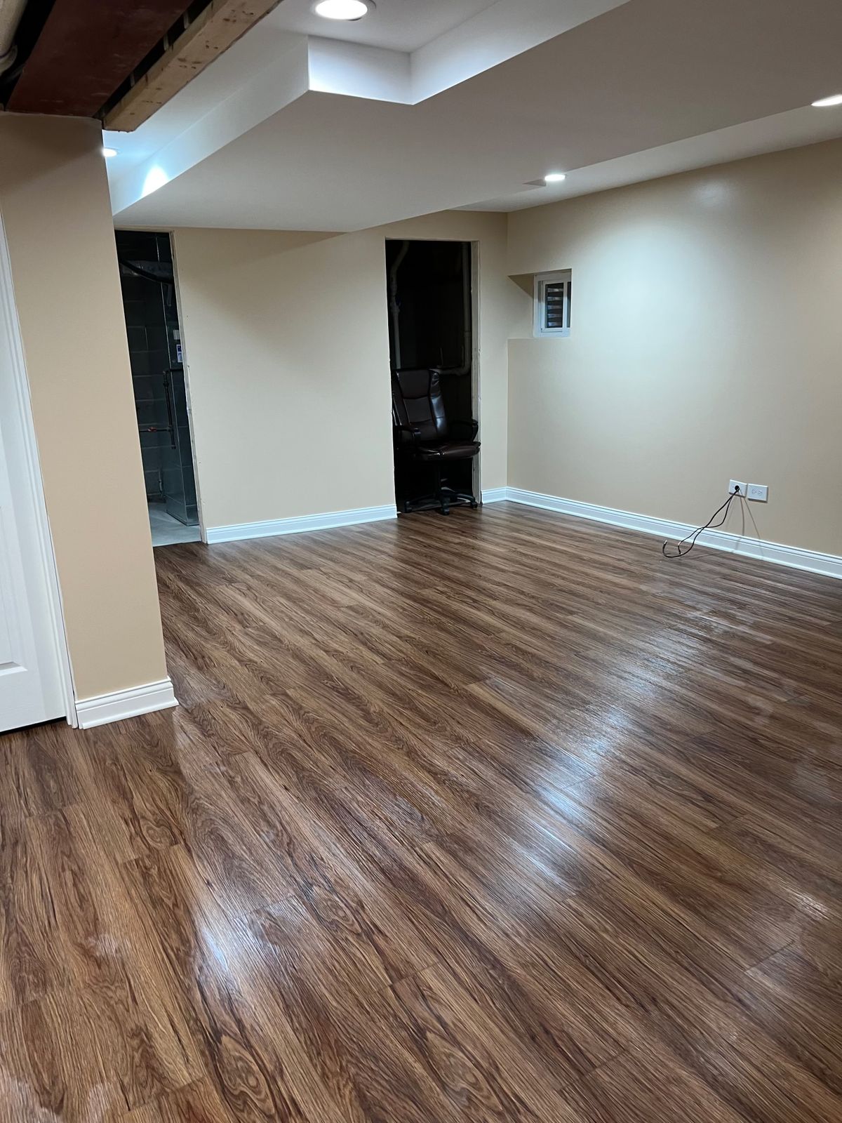 Finished basement with new brown vinyl plank floor and white baseboards